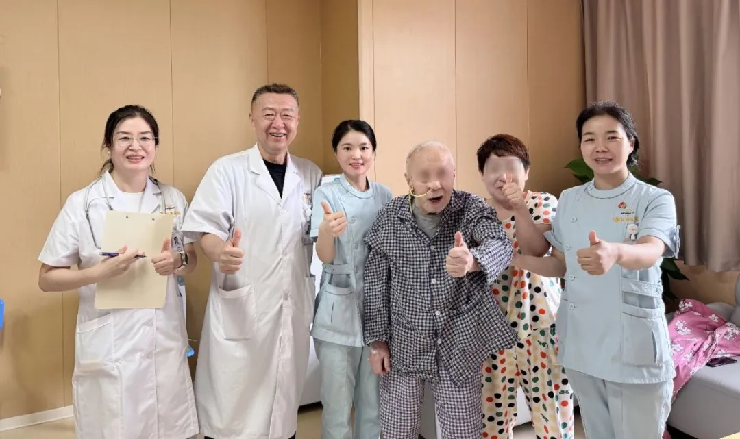 An 86-year-old patient giving a thumbs-up with the oncology and nursing team of Chang'an Hospital during ward rounds