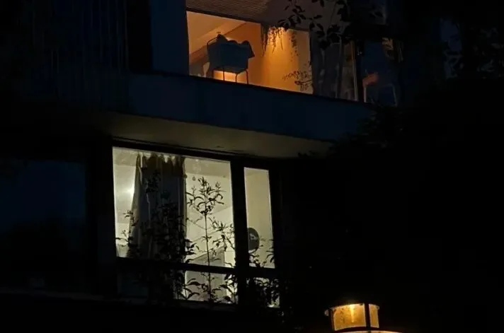 A quiet apartment building at night with warm light glowing from a single window